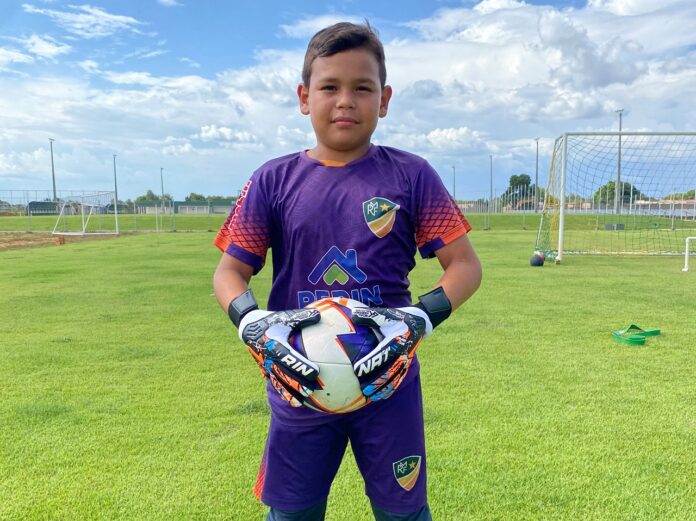 Goleiro José Vinícius segurando uma bola em um campo de futebol. Goleiro José Vinícius segurando uma bola em um campo de futebol.